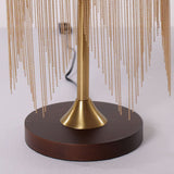 mid-century tassel table lamp glowing on a bedside table