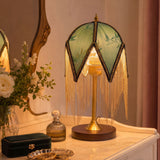mid-century tassel table lamp glowing on a bedside table